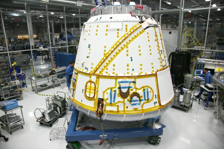 Anonymous male mechanic in uniform fixing detail of spacecraft while working at modern headquarter of industrial factory